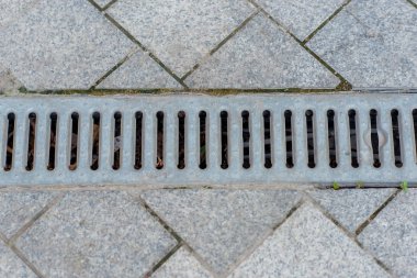 Kaldırım döşeme gri renk. Metal ızgaralı kaldırım için drenaj. Fırtına kanalizasyon drenaj. Drenaj unsurları. Bina.