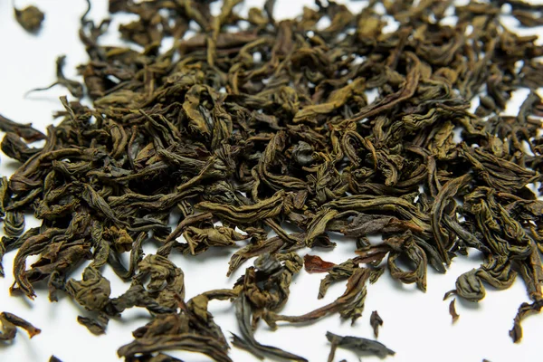 Leaf tea lies on a white background. Leaf tea storage. Natural product. Weighted green tea. Packing and sorting. The texture of dry leaves.