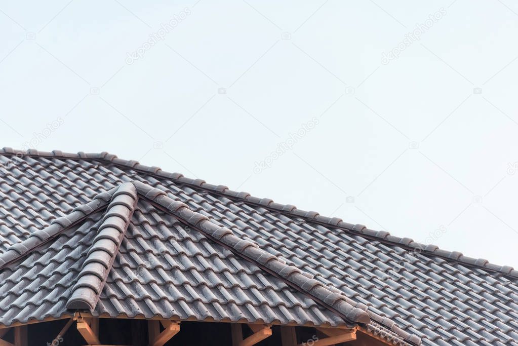 The roof of the house is covered with tiles. Dark gray tile. Building. House built of brick. Metal tile. Roof of the house. Exterior of the house. Roof structure. Ceramic tile.
