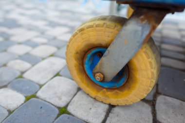Sarı Lastik tekerlekli metal bir arabası üzerinden. Döner tekerlek. İnşaat malzemeleri nakliye için katı lastik arabası. Bina. Demir çerçeve.