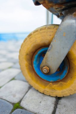 Sarı Lastik tekerlekli metal bir arabası üzerinden. Döner tekerlek. İnşaat malzemeleri nakliye için katı lastik arabası. Bina. Demir çerçeve.