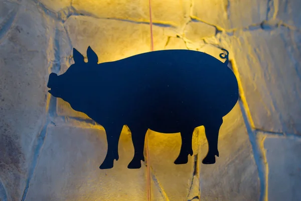 Plastic figure of a pig. Wall decor under the stone. Decorating the walls of restaurants. Decorative stone in the interior. Restroran. Installation of geometric shapes with yellow illumination.