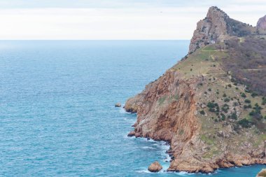 Mavi su. Kayalık sahil. Su yüzey dokusu. Dalgalar kayaların üzerinde yendi. Karadeniz. Yün çıkabilir. Yalta. Kırım'dinlenme. Sahil boyunca yürüyerek. Turizm.