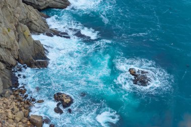 Mavi su. Kayalık sahil. Su yüzey dokusu. Dalgalar kayaların üzerinde yendi. Cliff. Karadeniz. Yün çıkabilir. Yalta. Kırım'dinlenme. Sahil boyunca yürüyerek. Turizm.