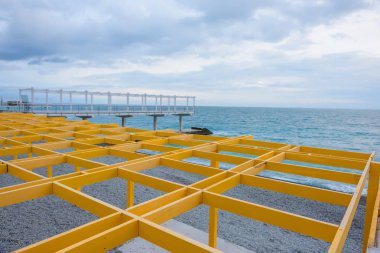 Metal yapılar sarı boyalı. Gölgelik. Karadeniz. Kayalık plaj. Su yüzeyi. Massandra plaj. Yalta dinlenme Kırım '. Plaj boyunca yürümek.