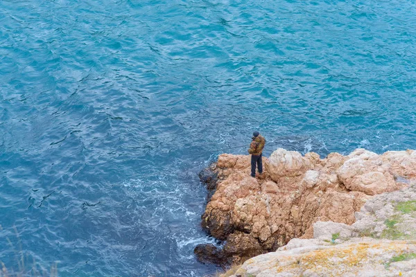 Embankment Balaclava Homem Pescador Pega Peixe Água Azul Costa Rochosa — Fotografia de Stock