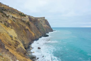 Kayalık sahil deniz kenarında. Karadeniz. Büyük kayalar ve kayalar. Dalgalar gürültüyle çarpmak buzlu. Bir sprey su. Kayalık plaj. Renkli moss buzlu. Kırım'dinlenme. Sevastopol. Yolculuk. Turizm.