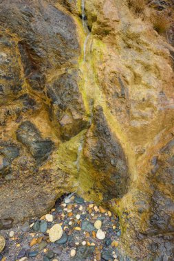 Kayalık sahil deniz kenarında. Karadeniz. Büyük kayalar ve kayalar. Taş dokusu. Yeşil yosun ve silt taş yüzeyinde. İçme suyu ile bahar. Kırım'dinlenme. Sevastopol. Yolculuk. Turizm.