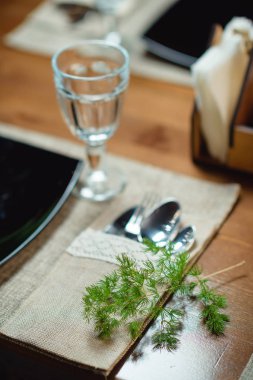 Festival Tablo ayarı. Çatal bıçak takımı. Ahşap masa. Cam gözlük. Masa dekor bitkiler. Ladin dal. Tablo için kumaş peçete. Siyah renkli bir tabak.