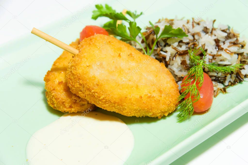 Chicken cutlets with a side dish in the form of multi-colored rice. Cherry tomatoes. Fresh parsley leaves. Food photography. Dinner. Meat dish in a light blue plate.