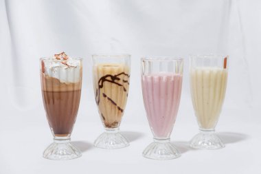 Milkshake cam bardak. Süt-karamel kokteyl ile bir kaşık dondurma. Çilekli kokteyl. Kahve krem şanti ile kokteyl. Gıda Fotoğrafçılık. Hisse senedi kokteyller.