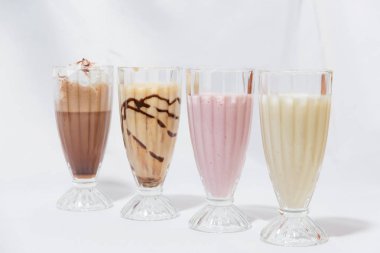 Milkshake cam bardak. Süt-karamel kokteyl ile bir kaşık dondurma. Çilekli kokteyl. Kahve krem şanti ile kokteyl. Gıda Fotoğrafçılık. Hisse senedi kokteyller.
