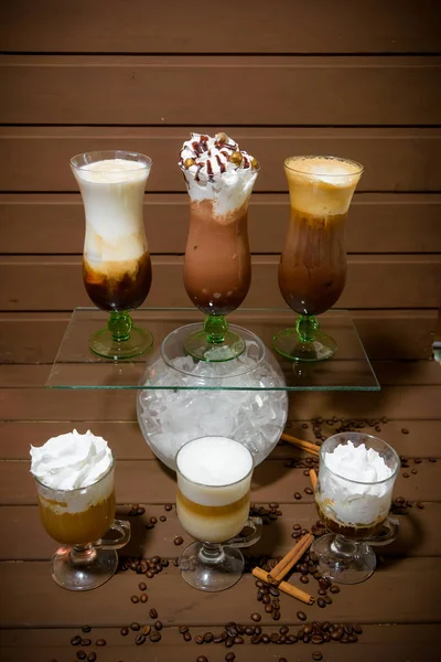 Coffee assortment. Coffee with a scoop of ice cream. Coffee with whipped cream. Mocha. Espresso with a scoop of ice cream. Cinnamon sticks and coffee beans. Different types of coffee in glass cups.