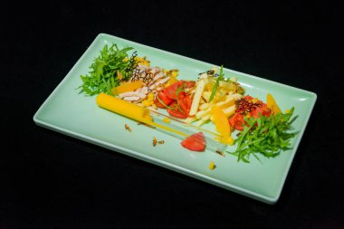 Sebze ve roka salatası. Domates ve salatalık. Tavuk göğsü ve patates kızartması. Mavi bir seramik tabak taze salata. Siyah bir arka plan üzerinde çanağı. Bir cam şişeye sos.