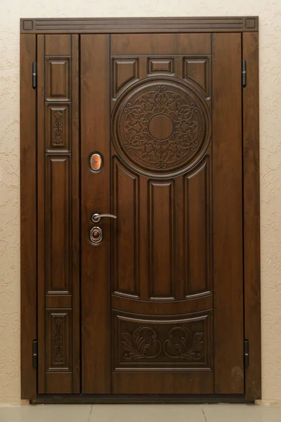 The door is sheathed in wood. Wood carving. Internal lock design. Keyhole. Metal door handle. Anti-burglar armored door. Metal doors. The design of the door. Peephole.