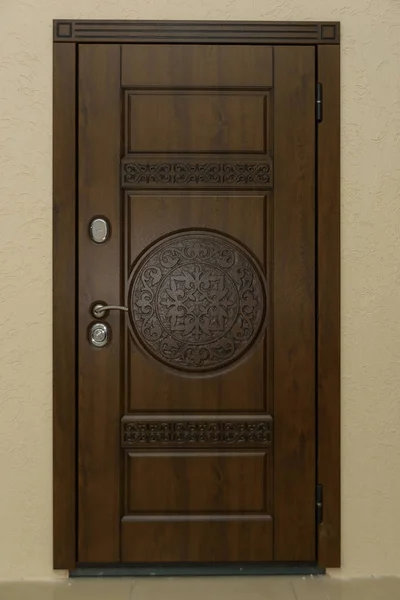 The door is sheathed in wood. Wood carving. Internal lock design. Keyhole. Metal door handle. Anti-burglar armored door. Metal doors. The design of the door. Peephole.