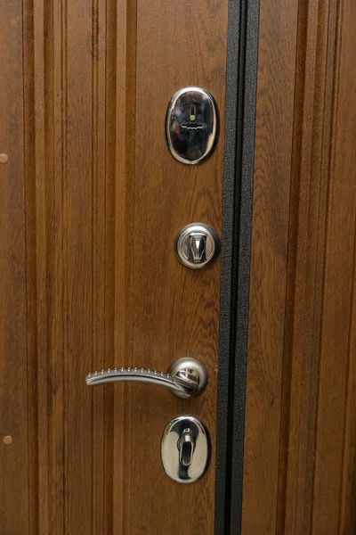The door is sheathed in wood. Wood carving. Internal lock design. Keyhole. Metal door handle. Anti-burglar armored door. Metal doors. The design of the door. Peephole.
