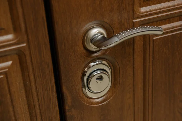 Wooden door. Internal lock design. Keyhole. Metal door handle. Anti-burglar armored door. Metal interior doors. The design of the door. Peephole.