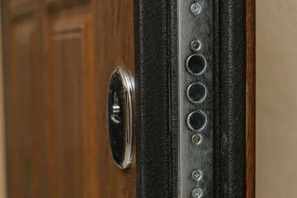 Wooden door. Internal lock design. Keyhole. Metal door handle. Anti-burglar armored door. Metal interior doors. The design of the door. Peephole.