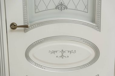 Kapı beyaz boyalı. Ahşap oyma. Metal kapı kolu. Anti-hırsız zırhlı kapı. Metal iç kapılar. Kapı tasarımı. İç.