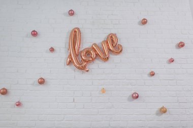 Noel dekor. Beyaz tuğla duvar pembe Noel topları ile dekore edilmiştir. Folyo balon bir yazıt sevgi ile. Photozone. Tuğla duvar dokusu. İç.