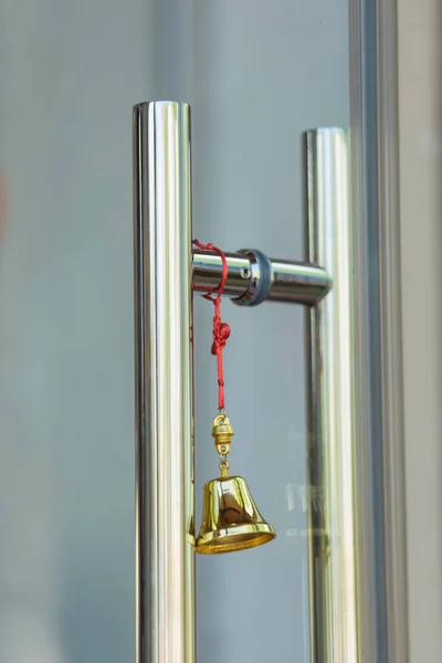 Golden bell on a red rope. Metal construction. Feng Shui mascot. Bell on the suspension with a knot of happiness. Charm.