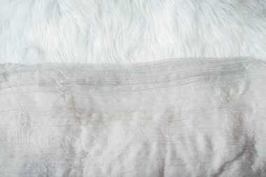 Kabarık beyaz battaniye. Şeffaf tül yatak örtüsü üzerinde yatıyor. Faux kürk kumaş dokusu.