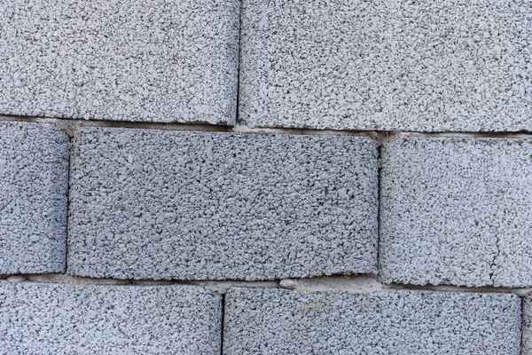 The texture of the fence of gray cinder block. Fence of building stone. Cinder block fence.