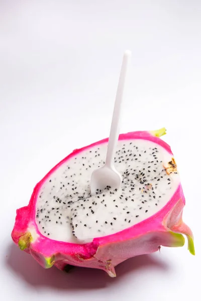 Exotic fruit. Dragon fruit. Red pitaya. Pitahaya pulp with black seeds. Sweet pitaya on white background. Cut dragon fruit. Pitaya with white flesh. Plastic white boat in pitaya.