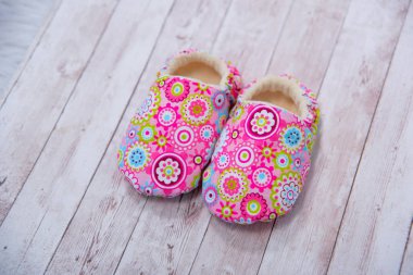 Yeni doğan kumaş terlik. Ayakkabı malzemeden yapılmış. Pembe patik yeni doğan. Patik çok renkli malzemeden yapılmış. Küçük çocuklar için terlik. Ahşap arka plan üzerinde bebek terlik.