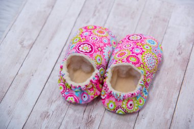Yeni doğan kumaş terlik. Ayakkabı malzemeden yapılmış. Pembe patik yeni doğan. Patik çok renkli malzemeden yapılmış. Küçük çocuklar için terlik. Ahşap arka plan üzerinde bebek terlik.