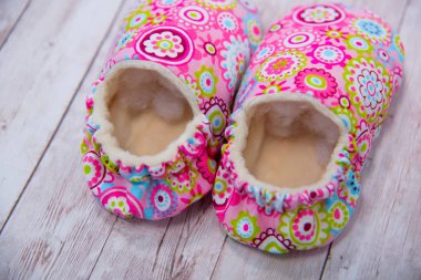 Yeni doğan kumaş terlik. Ayakkabı malzemeden yapılmış. Pembe patik yeni doğan. Patik çok renkli malzemeden yapılmış. Küçük çocuklar için terlik. Ahşap arka plan üzerinde bebek terlik.