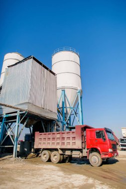 Damperli kamyon çimento olarak yüklenmemesi. Sanayi. Çimento fabrikası. Çimento üretim. Kargo kendini boşaltma araba kırmızı. Ulaşım çimento. Kırmızı Damperli kamyonlar.