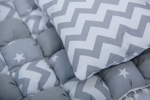 新生儿的枕头 新生儿的毯子和枕头 织物的纹理 枕头保险杠 婴儿床里枕头的两侧 打印锯齿形星 — 图库照片