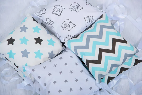 Pillows for newborns. Pillows bumpers. Set of pillows for a baby cot. The texture of the fabric. Print with bears and stars. The sides of the pillow in the crib.