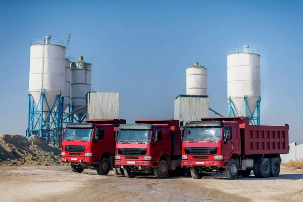 Loading of cement in the dump truck. Industry. Cement plant. Cement production. Cargo self-unloading car red. Transportation of cement. Red dump trucks.