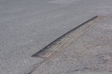 Asfalt yol. Çatlak ve delikler içinde belgili tanımlık yol. Asfalt. Asfalt kaplama doku. Hasarlı yüzey. Bir yarık içinde belgili tanımlık yol.