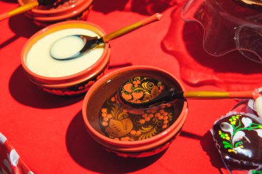 Rus dinlerde sofra. Rus ahşap oyuncak boyalı bez bebek şeklinde. Ahşap boyalı çatal bıçak takımı. Taze çiçek demetleri. Kurutma ve zencefilli kurabiye. Kırmızı masa örtüsü. Khokhloma resim.