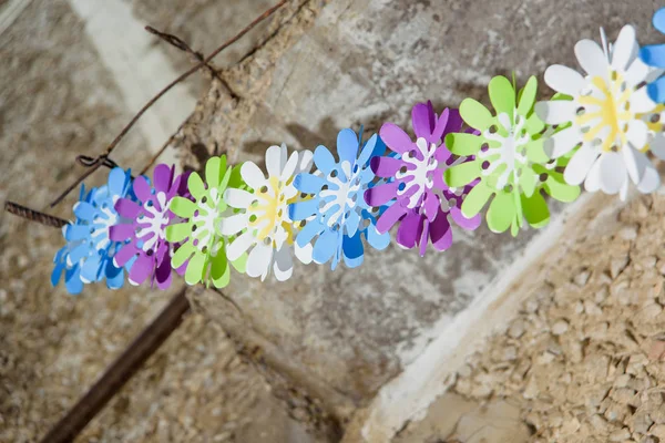 Decorative garland of paper flowers. Artificial flowers are on the concrete. The texture of the concrete coating.