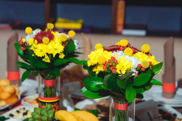 Table setting in Russian traditions. Russian wooden toy in the form of a painted doll. Wooden painted Cutlery. Bouquets of fresh flowers. Drying and gingerbread. Red tablecloth. Khokhloma painting.