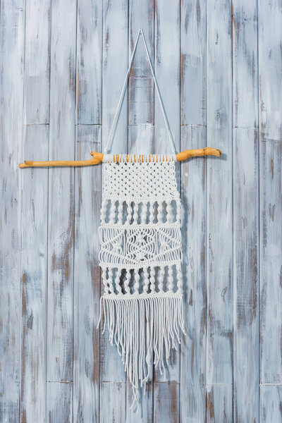 Macrame on a wooden wall. Handmade white thread decor. Decorating a house in a rustic style.