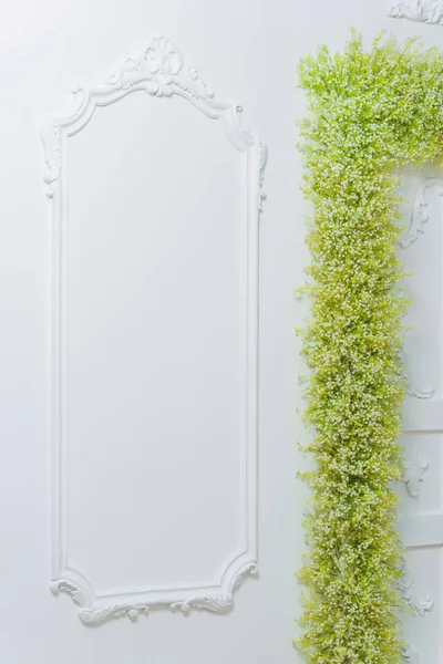 Spring decor. White walls. Beautiful stucco on the walls. Arch of green and white flowers. Photo zone. The decor of the doorway with flowers. White baby\'s breath.