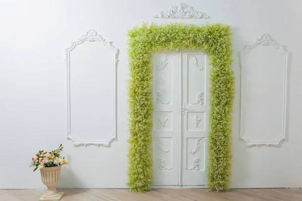 春天的装饰 白色的墙壁 墙上挂着漂亮的灰泥 绿色和白色的花的拱门 门口的装饰有鲜花 白色宝宝的呼吸 柱子上花瓶里的花束 — 图库照片
