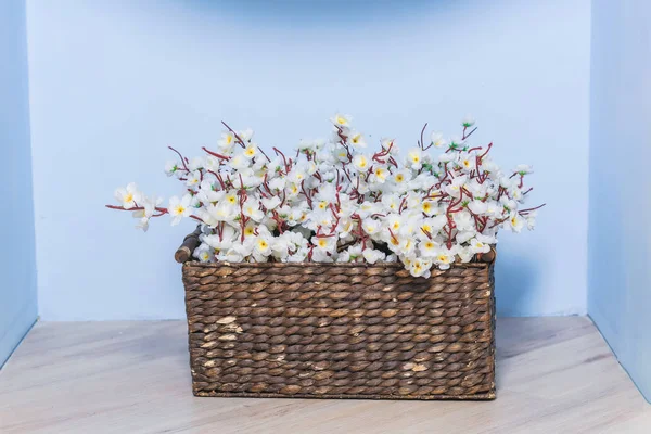 Spring decor. The walls are blue. Wicker brown basket with flowers. The interior of the room. Decorative element.