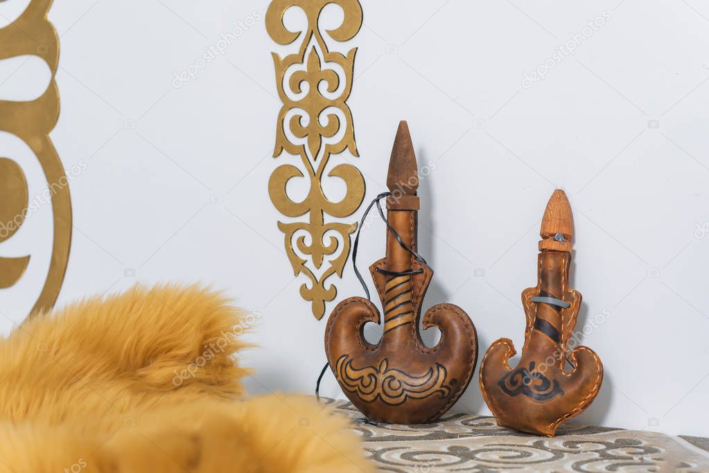 Kazakh national subjects. Gold ornaments on the white walls. Sheep skin decorative.  Leather container for storing drinks. Kazakh medieval shield. Wooden chest with patterns.