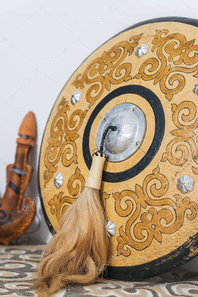 Kazakh national subjects. Gold ornaments on the white walls. Sheep skin decorative.  Leather container for storing drinks. Kazakh medieval shield. Wooden chest with patterns.