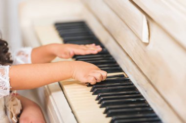 Retro Klasik piyano. Beyaz müzik aleti. Siyah ve beyaz anahtarlar. Çocukların elleri anahtarlara. Çocuk tutan kadın.