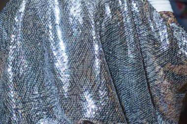 Pul ile kumaş dokusu. Parlak pelerinli bir kadın. Pullar ile dekore edilmiş peler. Elinde beyaz eldiven var. Restoranda etkinlik.