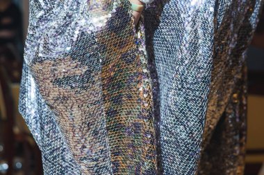 Pul ile kumaş dokusu. Parlak pelerinli bir kadın. Pullar ile dekore edilmiş peler. Elinde beyaz eldiven var. Restoranda etkinlik.