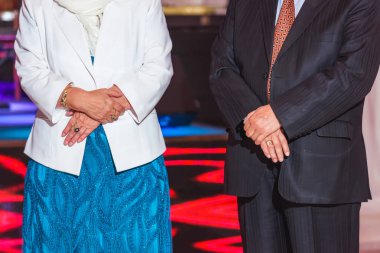 Yaşlı adam ve kadın sırada ayakta. Restoranda olay. Mavi elbiseyle ve Beyaz ceketli bir kadın. Klasik takım elbiseli bir adam.